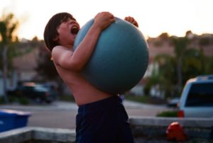 Image of child holding exercise ball and yelling